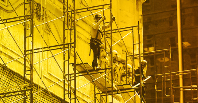 Two men on scaffolding doing construction on a building. Representing cybersecurity frameworks like NIST CSF 2.0.