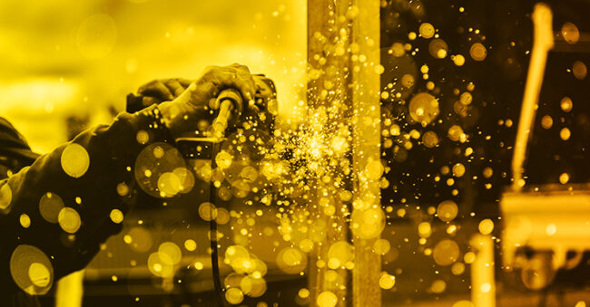 yellow monochrome image of a person welding with sparks to represent CMMC final rule