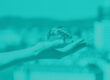 Teal one-toned image of a person holding a crystal ball in a cityscape depicting cybersecurity predictions
