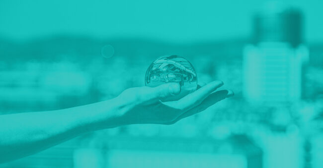 Teal one-toned image of a person holding a crystal ball in a cityscape depicting cybersecurity predictions