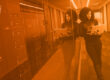Monochromatic orange image of woman in a server room representing cybersecurity compliance standards
