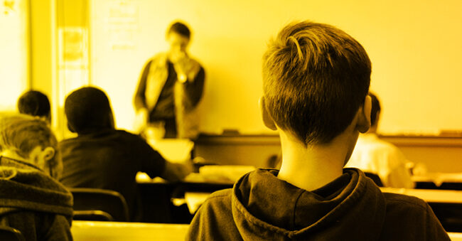 monochromatic yellow photo of the back of a young boy's head in a classroom signifying security awareness training for teachers