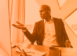 monochrome orange image of a man looking frustrated at a computer representing business email compromise payload