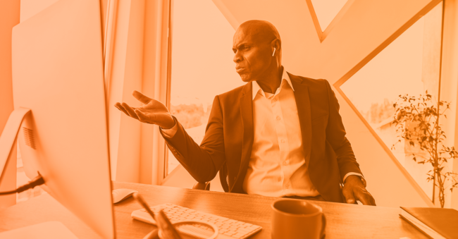 monochrome orange image of a man looking frustrated at a computer representing business email compromise payload cybersecurity ROI