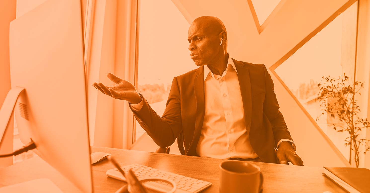 monochrome orange image of a man looking frustrated at a computer representing business email compromise payload