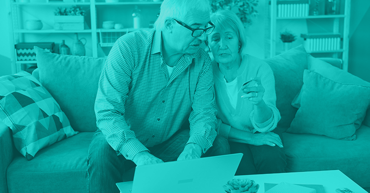 a teal monotone image of an older couple looking at a computer together with a credit card in hand to represent cybersecurity for older adults