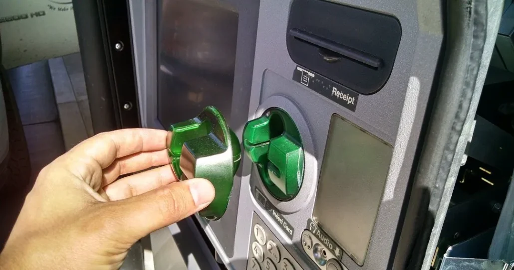 photo of a person's hand pulling a credit card skimmer off of an ATM's card reader showing a credit card fraud example
