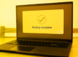 monotone yellow image of a laptop showing a software stating "backup complete," representing IDrive Backup CVE-2026-1995